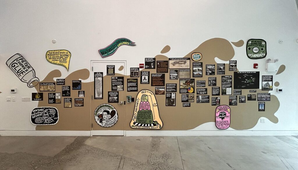 A large artwork installed on a wall, featuring text and painted imagery