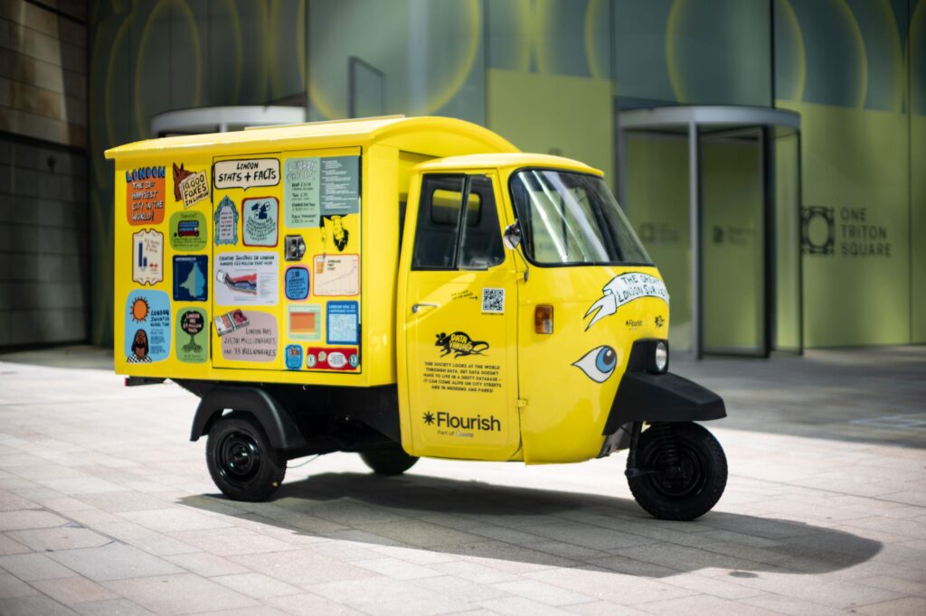 A small yellow vehicle covered in signs