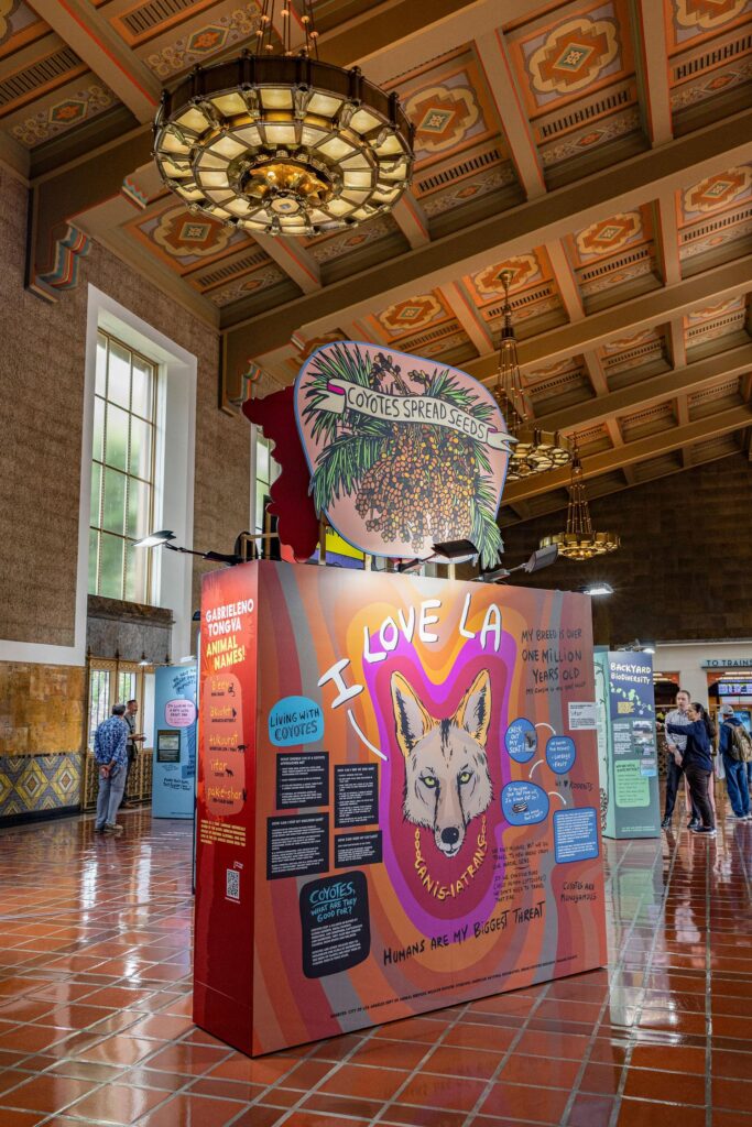 A large, indoor artwork featuring painted imagery and text