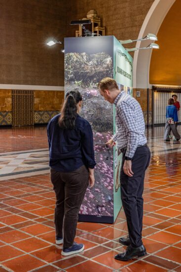 Two people looking at the side of a large artwork