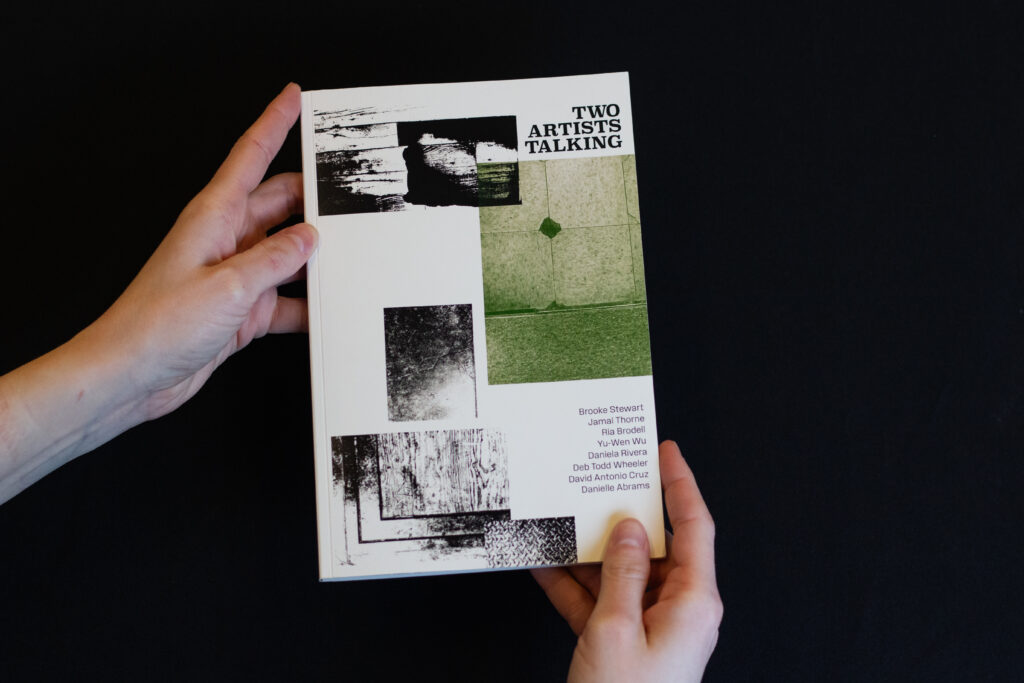 A book held by two hands against a black background