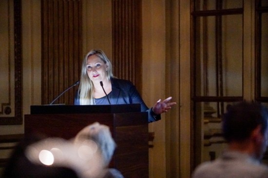 A photograph of a woman speaking from behind a podium
