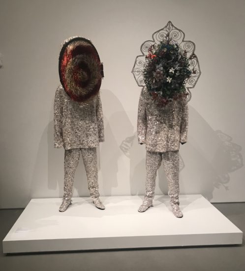 A photograph of two silver sequined costumes with elaborate headpieces