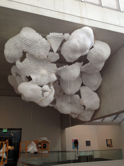 A photograph of the installation of a large, globular white sculpture.