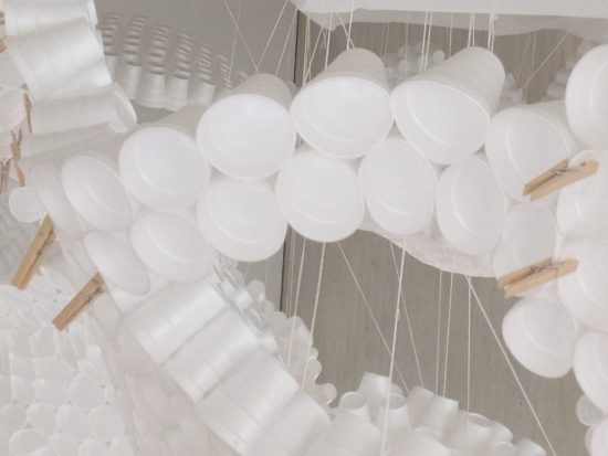 A photograph of white styrofoam cups joined together and suspended by strings