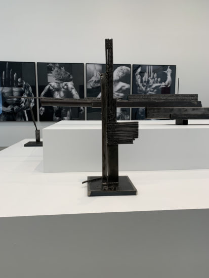 A photograph of artwork sitting on a pedestal and hanging on a wall