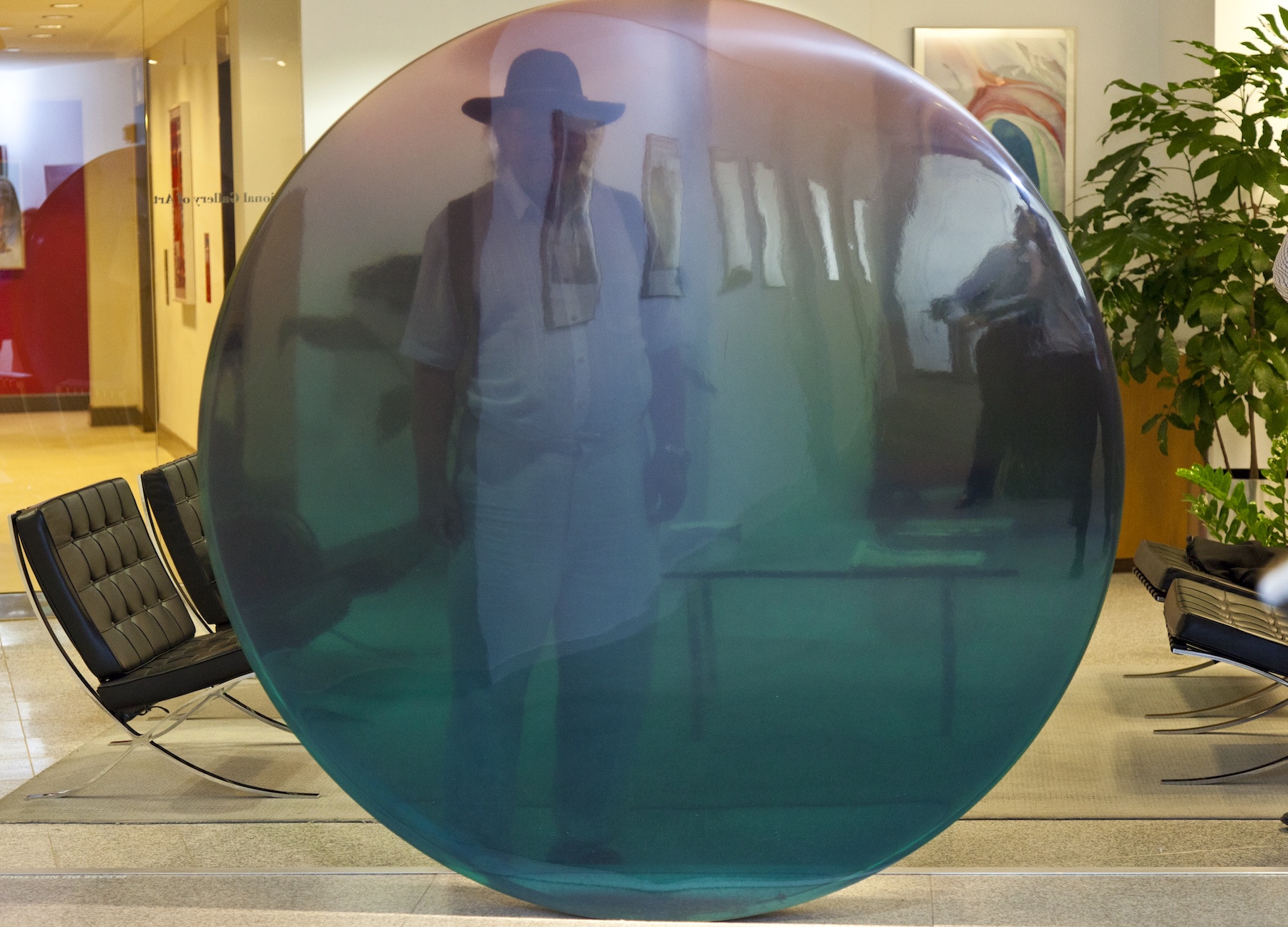 A photo of De Wain Valentine standing behind one of his translucent resin sculptures