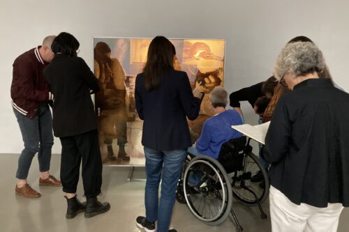A photo of 8 people observing a contemporary artwork lit from behind.