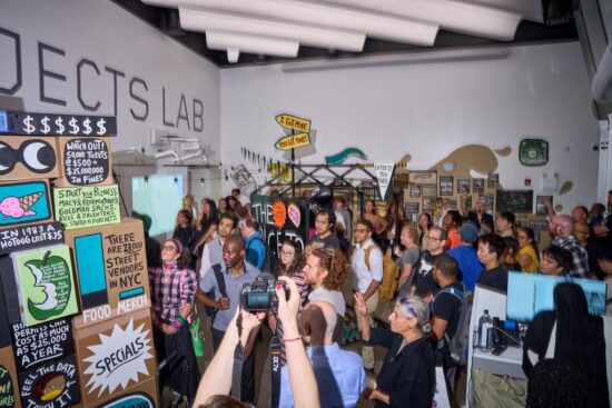 A large group of people standing near various artworks in an exhibition space