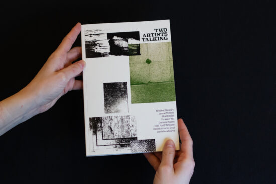 A book held by two hands against a black background